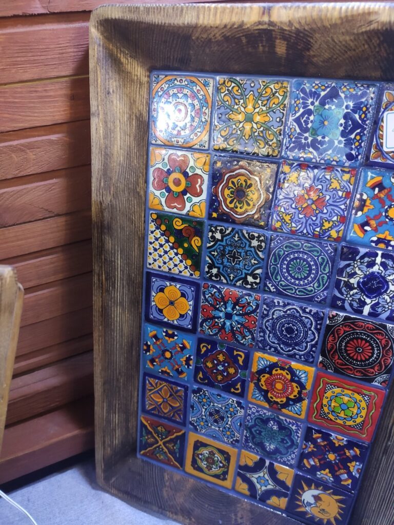 Zbliżenie na ceramiczną mozaikę osadzoną w drewnianej desce